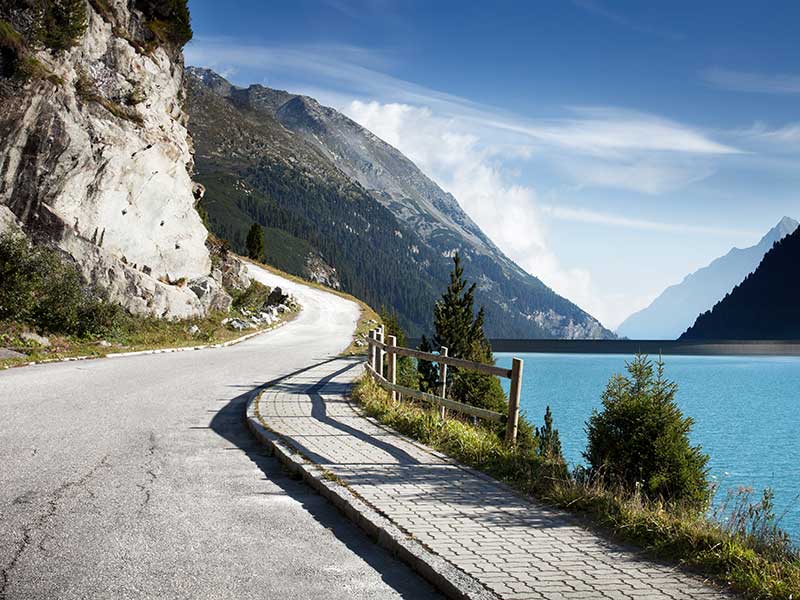 Kurvenreiche Straße entlang eines Berges mit See