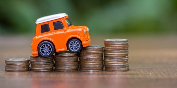 Spielzeugauto auf Münzstapel am Tisch