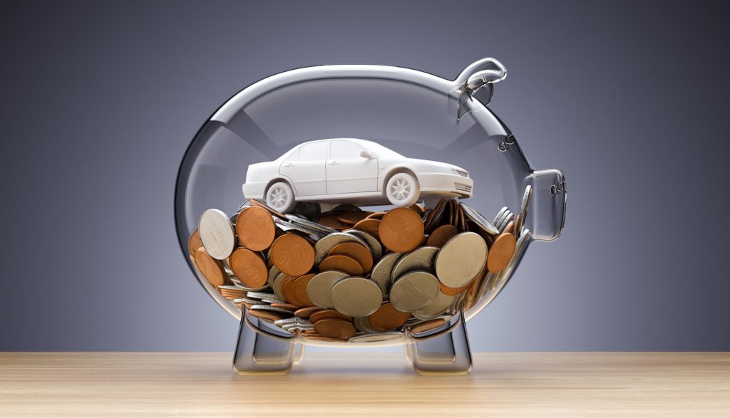 Gläsernes Sparschwein mit Geld und einem weißen Spielzeugauto darin