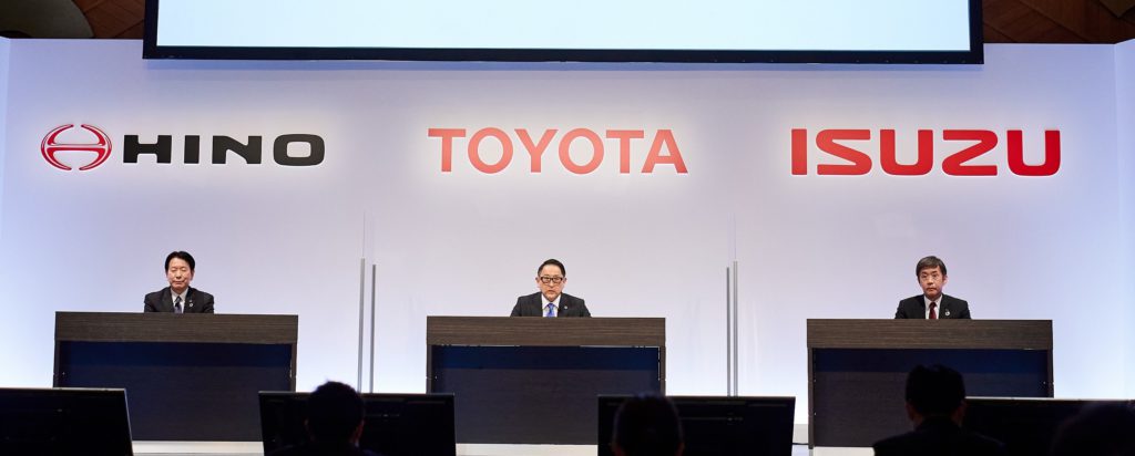 Pressesprecher mit Hino, Toyota und Isuzu Schriftzug im Hintergrund